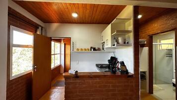 A compact kitchen with a wooden ceiling, a microwave, and a sink.