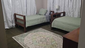 Una camera da letto con due letti singoli, una ventola a soffitto e un tappeto decorato.