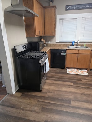 A kitchen with a stove, oven, microwave, and dishwasher. - The Shaded Pecan Cottage (Terrell)