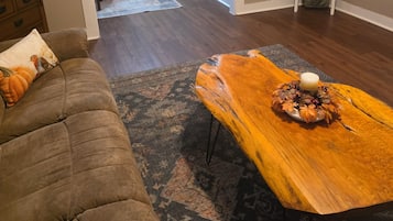 A living room with a sofa, a wooden coffee table with a candle, and a patterned rug.