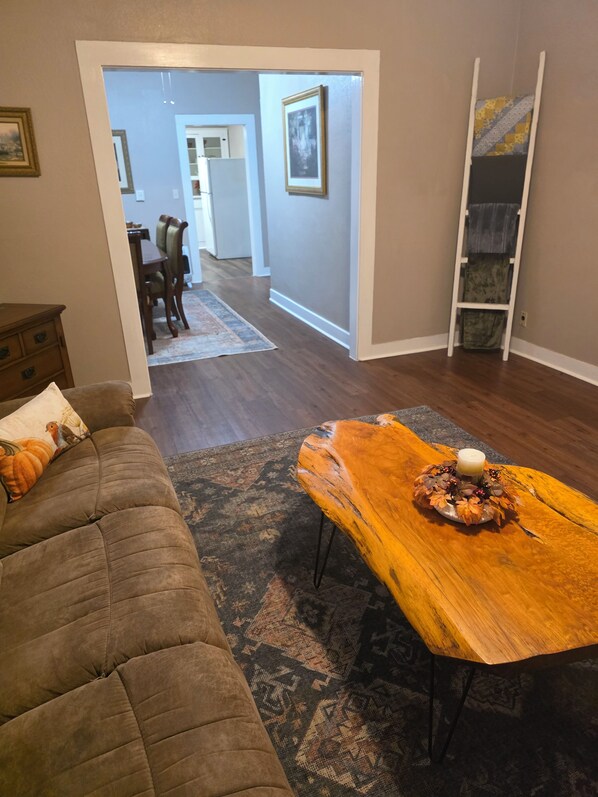 A living room with a sofa, a wooden coffee table with a candle, and a patterned rug.