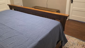 Een slaapkamer met een bed, een aan de muur bevestigde televisie en een houten hoofdeinde.