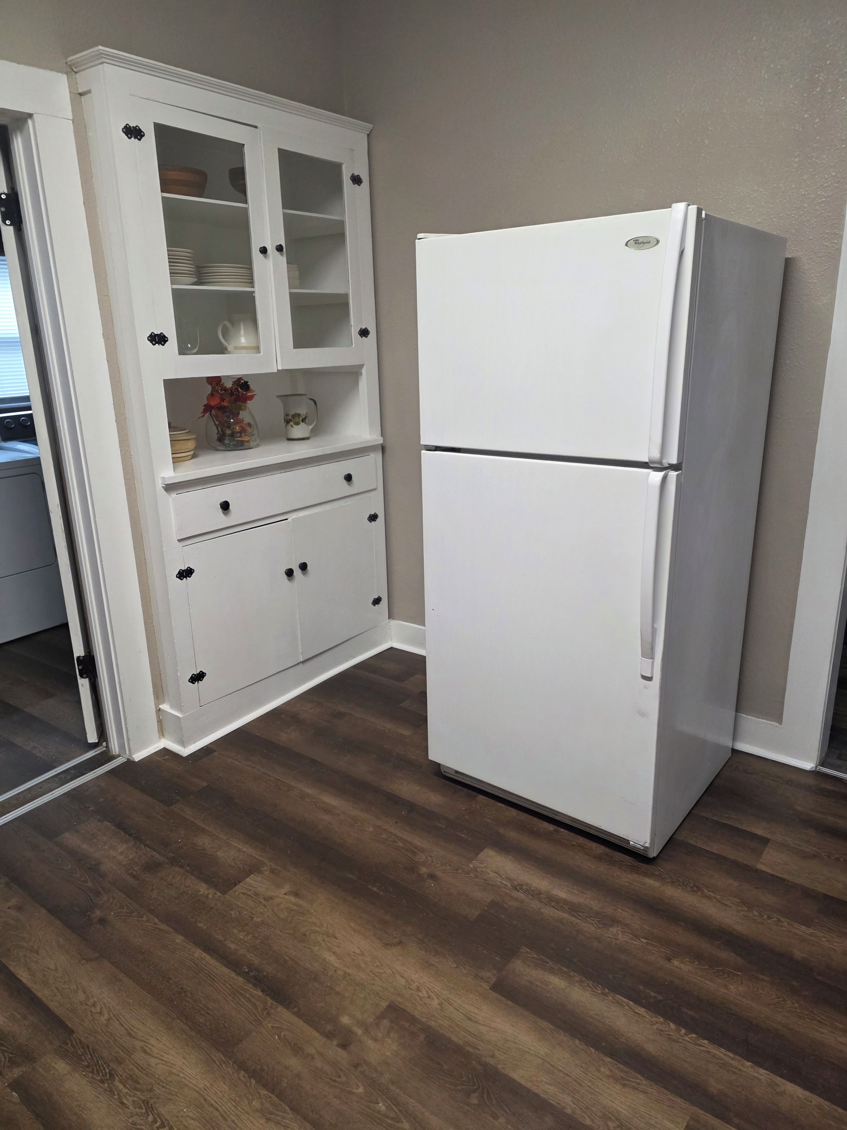 Een keuken met een witte koelkast, houten kasten en een houten vloer.