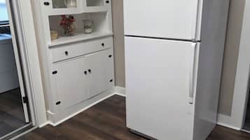 Een keuken met een witte koelkast, houten kasten en een houten vloer.