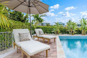 A poolside area with lounge chairs and an umbrella. - Sunny Daze~Private Pool Home, 45ft of Dockage, minutes from the beach! (Marathon)