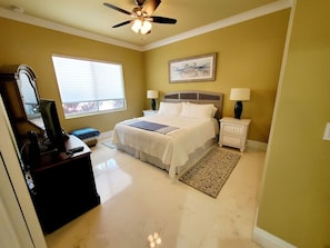 A bedroom with a bed, bedside lamps, a ceiling fan, a window with blinds, and a television on a stand. - Sunny Daze~Private Pool Home, 45ft of Dockage, minutes from the beach! (Marathon)