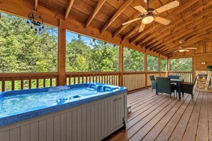 Eine Holzterrasse mit Whirlpool, Gartenmöbeln und Deckenventilator.
