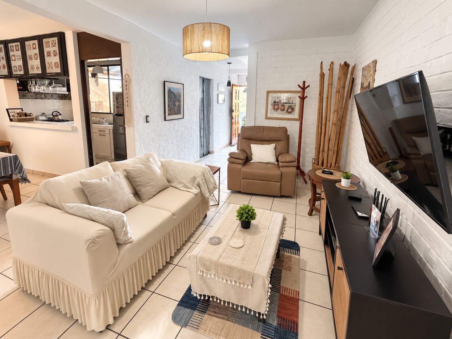 Un salon moderne avec un canapé, un fauteuil et un téléviseur posé sur un meuble.