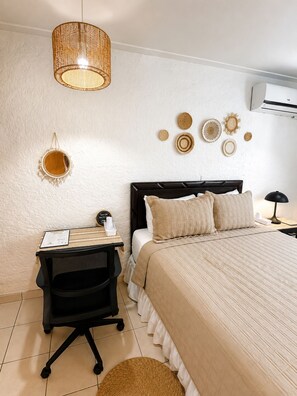A bedroom with a bed, bedside table, chair, and a hanging light fixture. - La Casa del Pasaje (San Salvador)