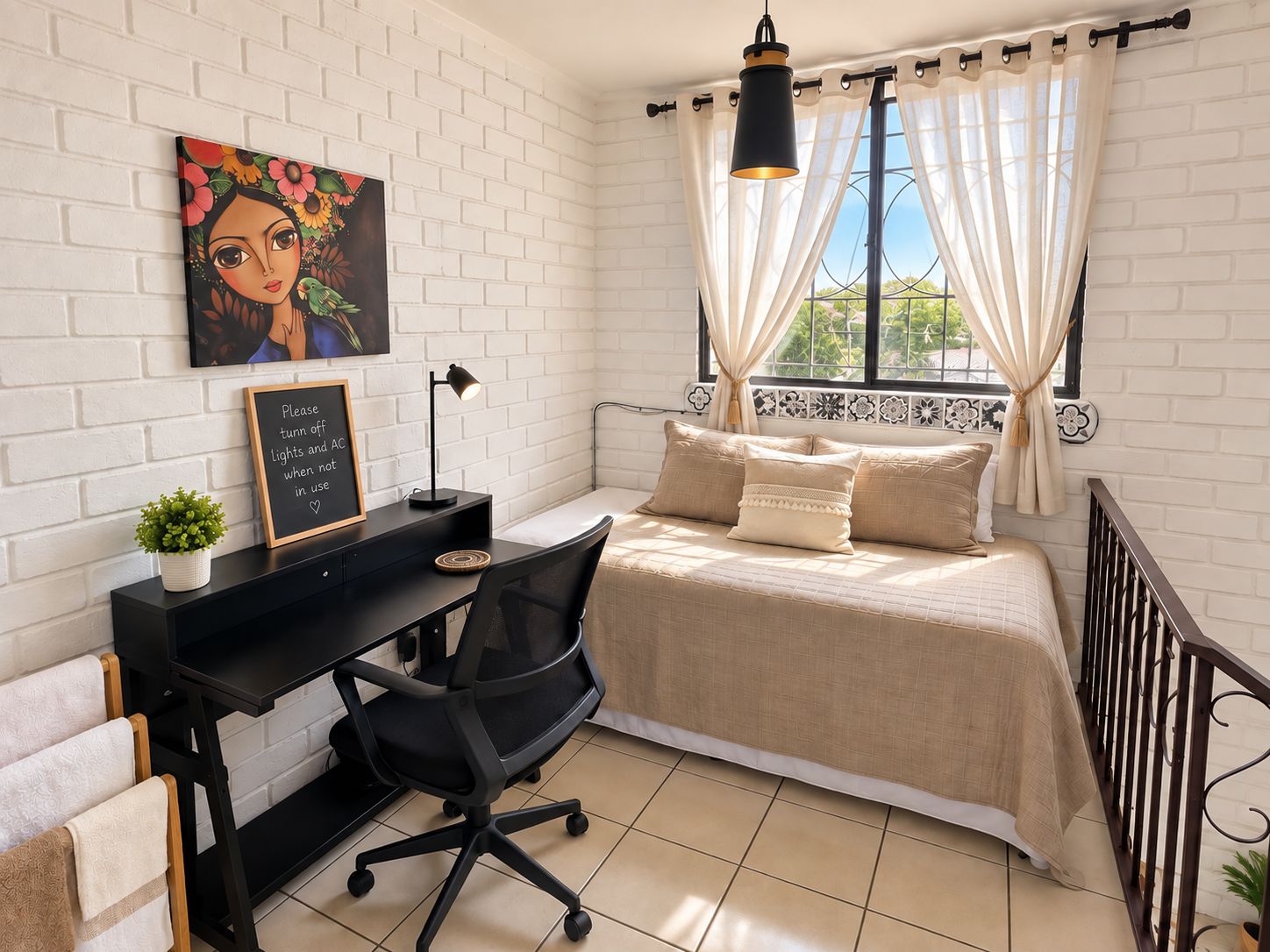 Une chambre à coucher avec un lit, un bureau avec une chaise, une petite plante, un tableau accroché au mur et une fenêtre avec des rideaux.