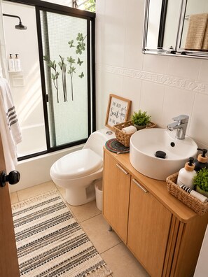 A modern bathroom with a toilet, bidet, and sink. There is a window with a view of greenery outside. - La Casa del Pasaje (San Salvador)