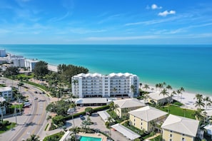 A beachfront hotel with multiple floors, a swimming pool, and a view of the ocean. - Beachfront Escape in the Moorings | Gulf Views & Coastal Breeze (Naples)