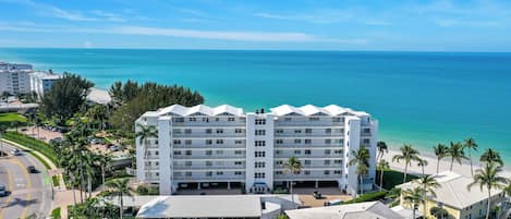 Un hôtel à plusieurs étages doté d’une piscine, situé près d’une plage aux eaux d’un bleu cristallin.