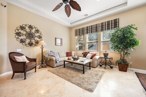 A living room with a sofa, armchair, coffee table, decorative wall art, and a potted plant. - 2 bed, 2.5 bath Oasis: Clubhouse, Pool, Gym- Steps to Polo Concerts Golf Tennis! (La Quinta)