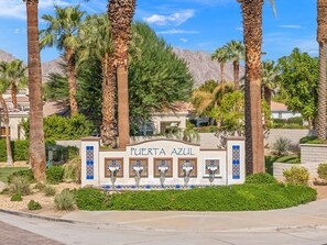 A sign for 'PUERTA AZUL' with a tiled facade and a fountain in front. - 2 bed, 2.5 bath Oasis: Clubhouse, Pool, Gym- Steps to Polo Concerts Golf Tennis! (La Quinta)
