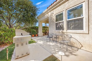 An outdoor patio with a barbecue grill, seating area, and a building with large windows. - 2 bed, 2.5 bath Oasis: Clubhouse, Pool, Gym- Steps to Polo Concerts Golf Tennis! (La Quinta)