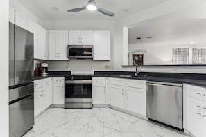 A modern kitchen with white cabinets, stainless steel appliances, and a marble floor. - Remodeled 3BR Kierland | Garage, Pool, Spa, Golf (Scottsdale)