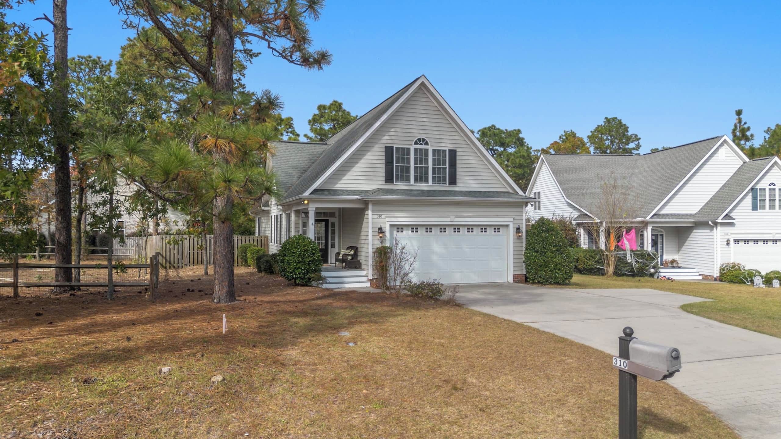 A residential area with two houses, each featuring a garage, a front porch, and a well-maintained lawn.