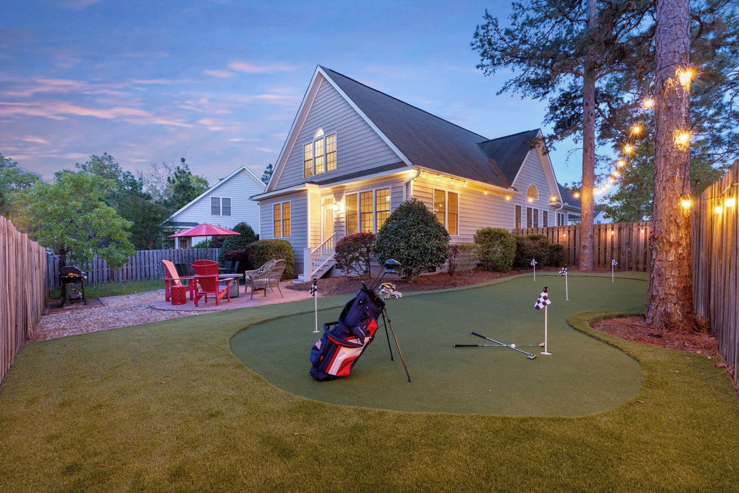 Een woonhuis met een verzorgd gazon, een golfkar en een woning met een veranda.