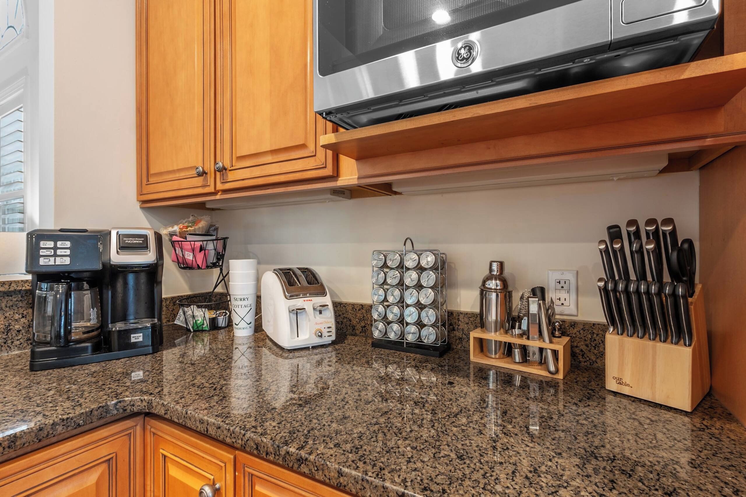 A kitchen with wooden cabinets, a coffee maker, a toaster, a spice rack, and a knife block.