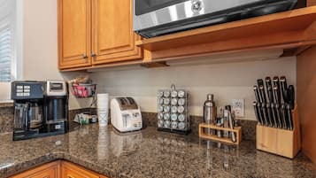 A kitchen with wooden cabinets, a coffee maker, a toaster, a spice rack, and a knife block.