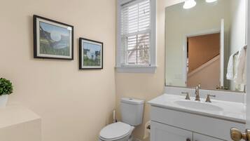 A bathroom with a toilet, sink, and two framed pictures on the wall.