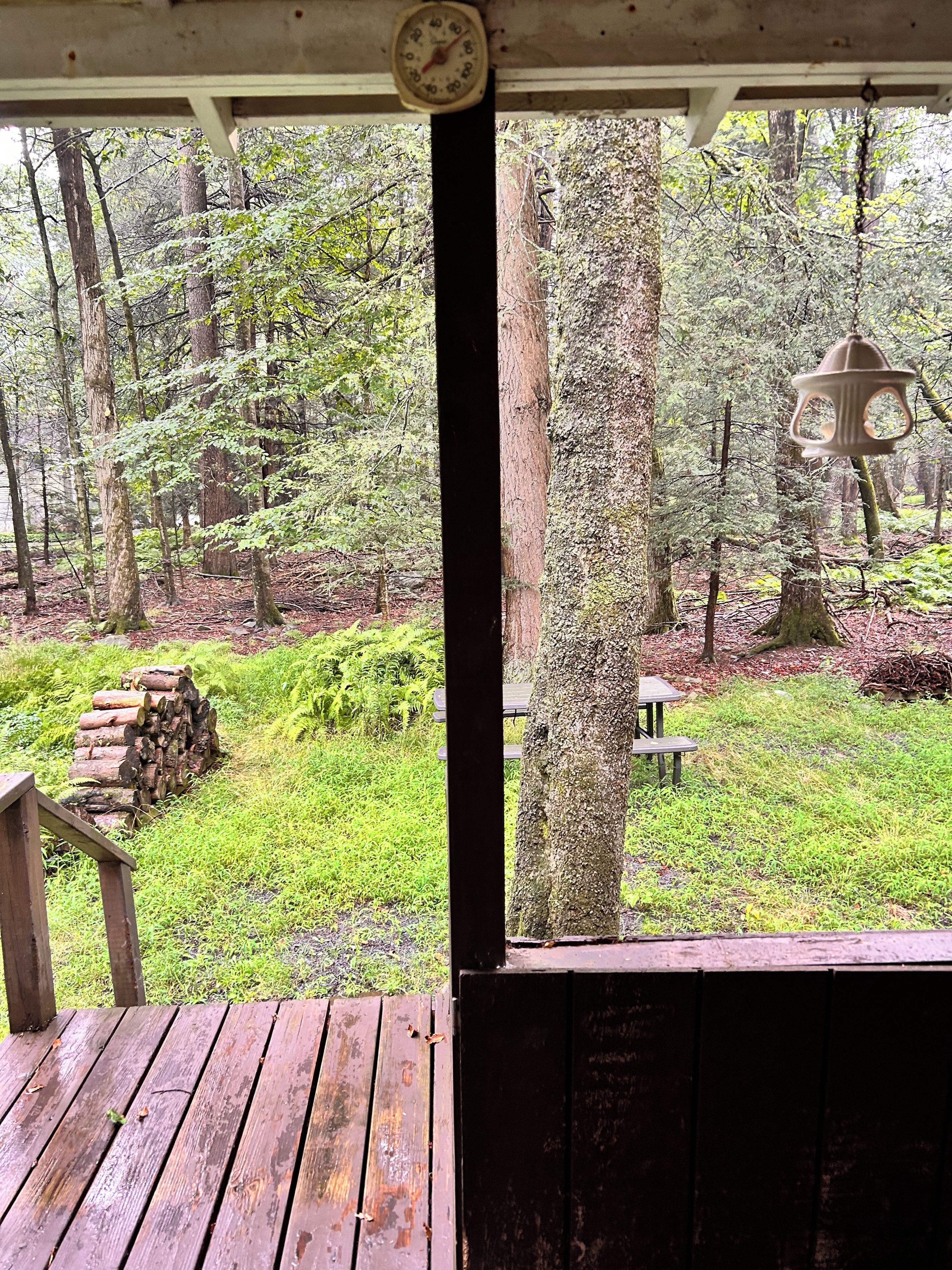 A wooden deck with a rustic bench, a stack of firewood, and a picnic table.