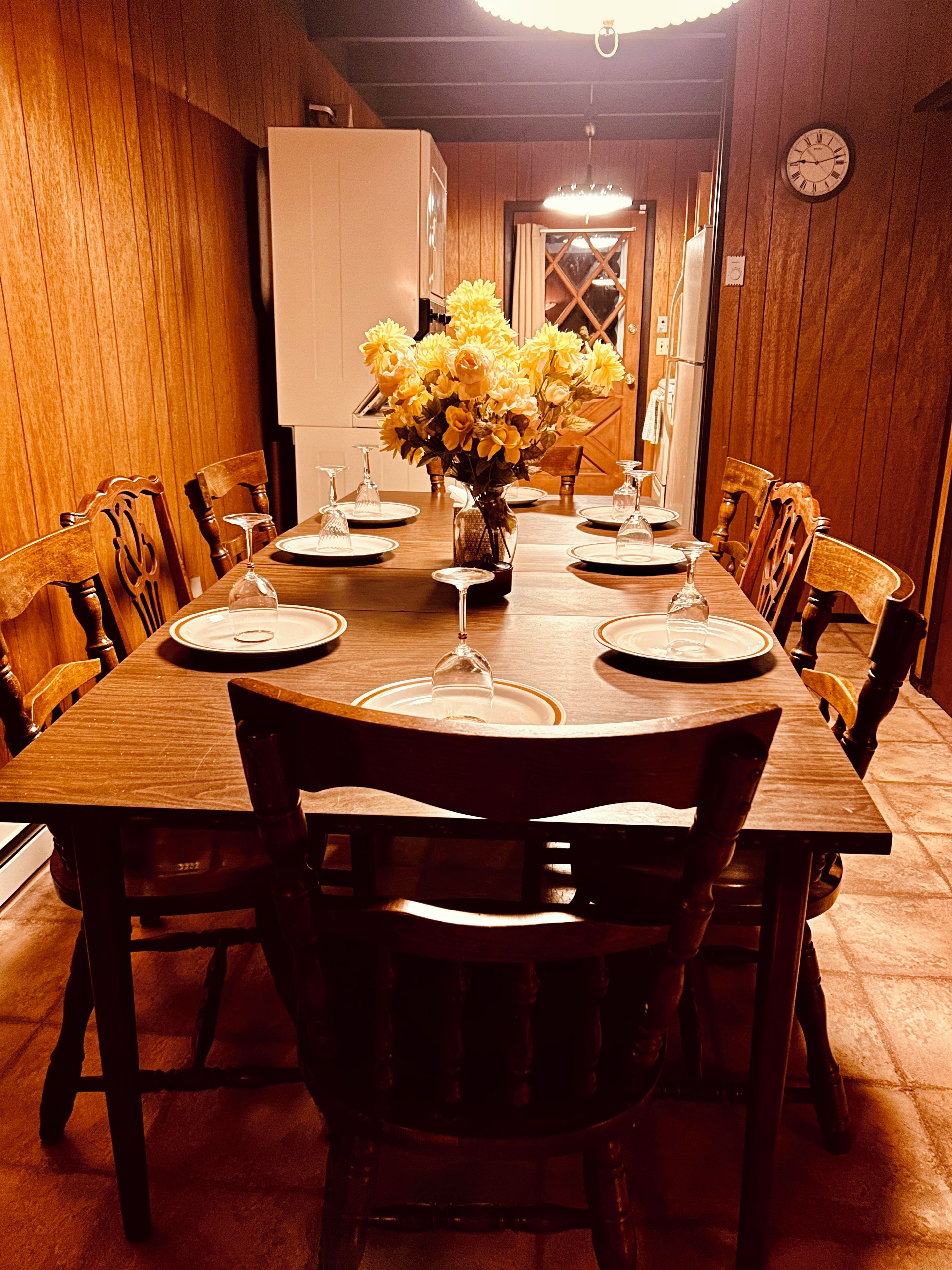 A dining table set with plates, glasses, and a vase of yellow flowers.