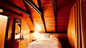 A bedroom with a wooden ceiling, a bed, a dresser, and a mirror.