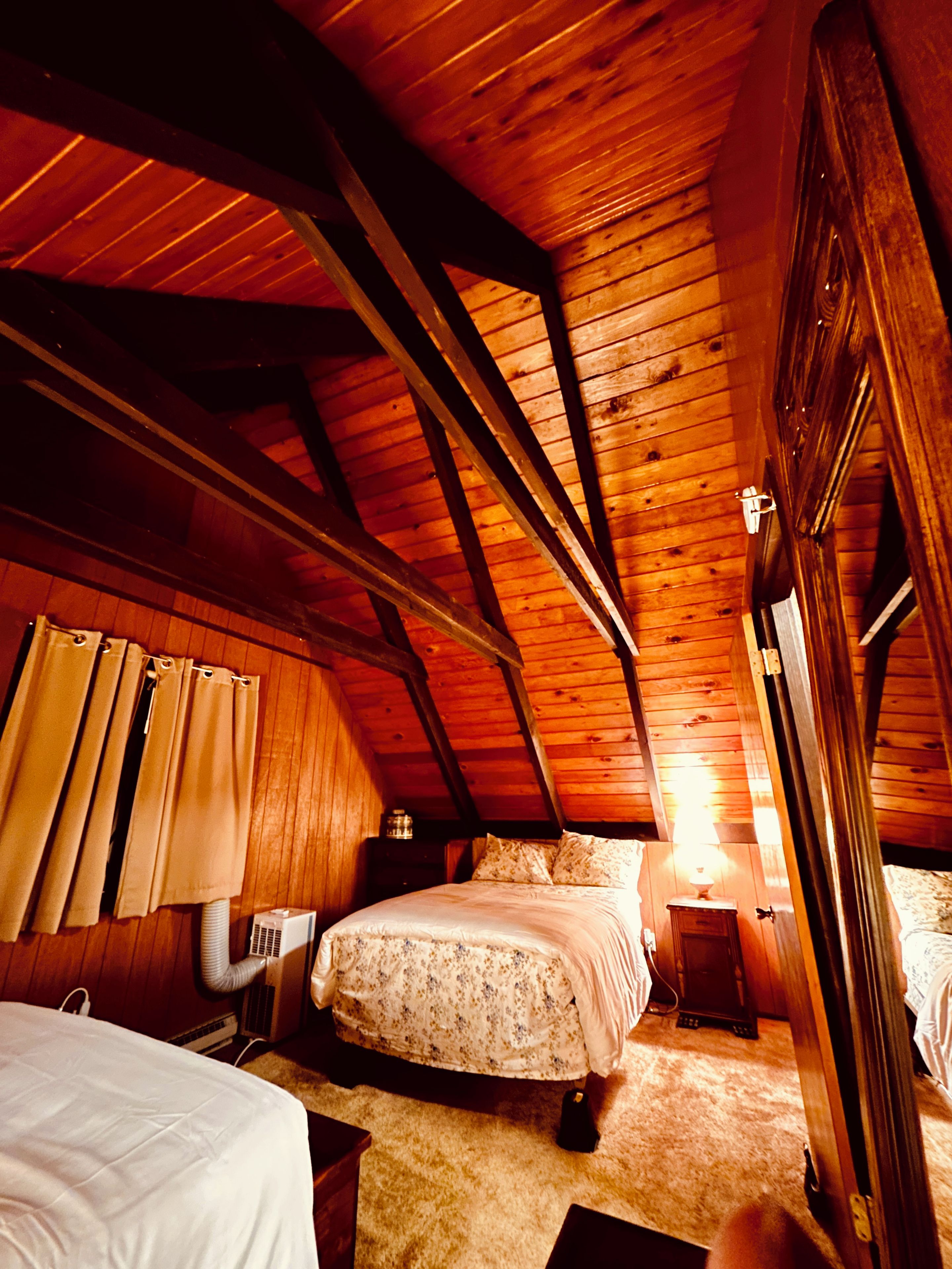 A bedroom with a sloped ceiling, a bed, a bedside table, and a heater.