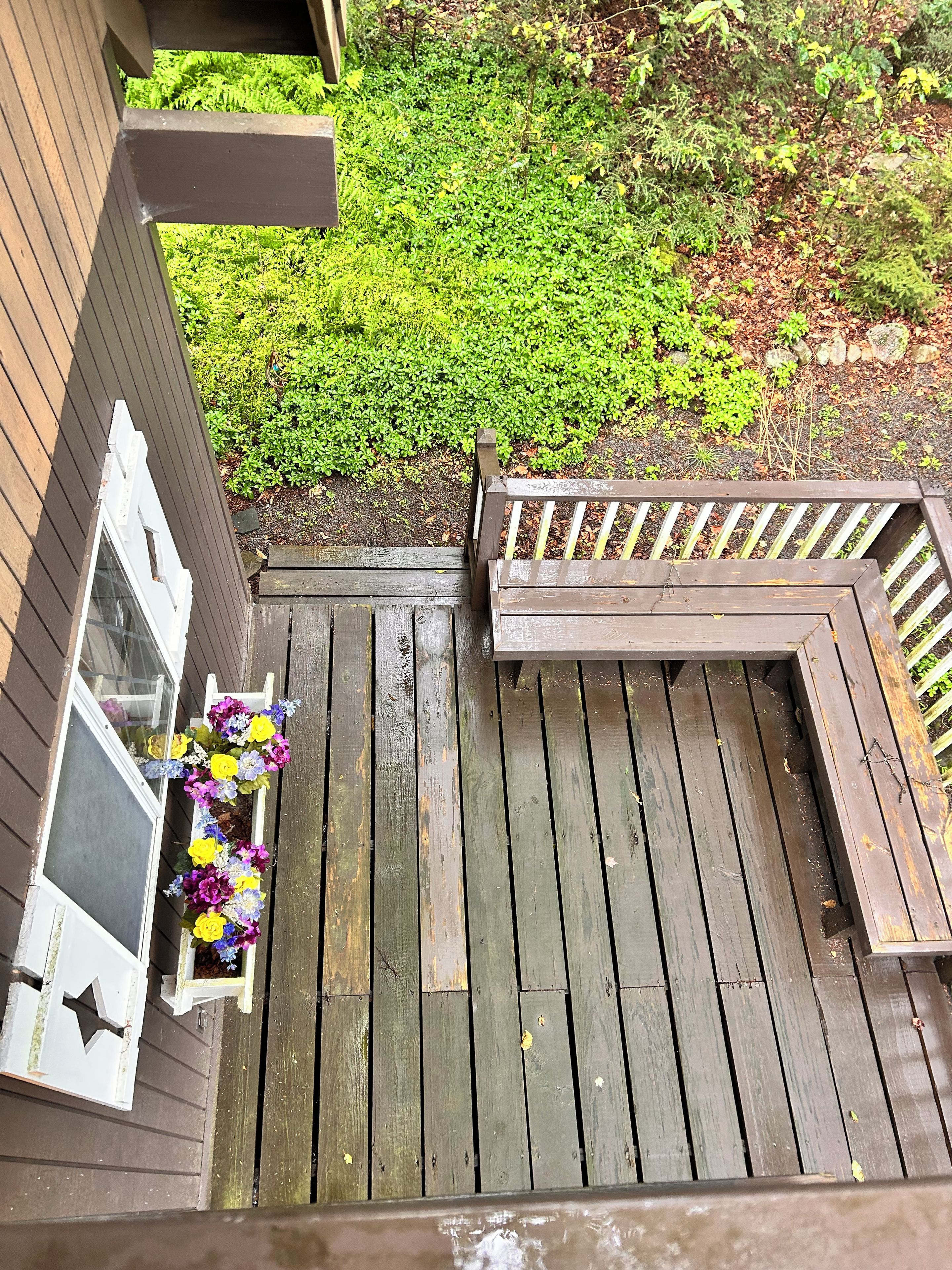 A wooden deck with a bench and a planter with flowers.