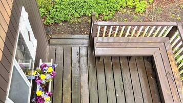 A wooden deck with a bench and a planter with flowers.