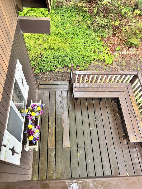 A wooden deck with a bench and a planter with flowers.