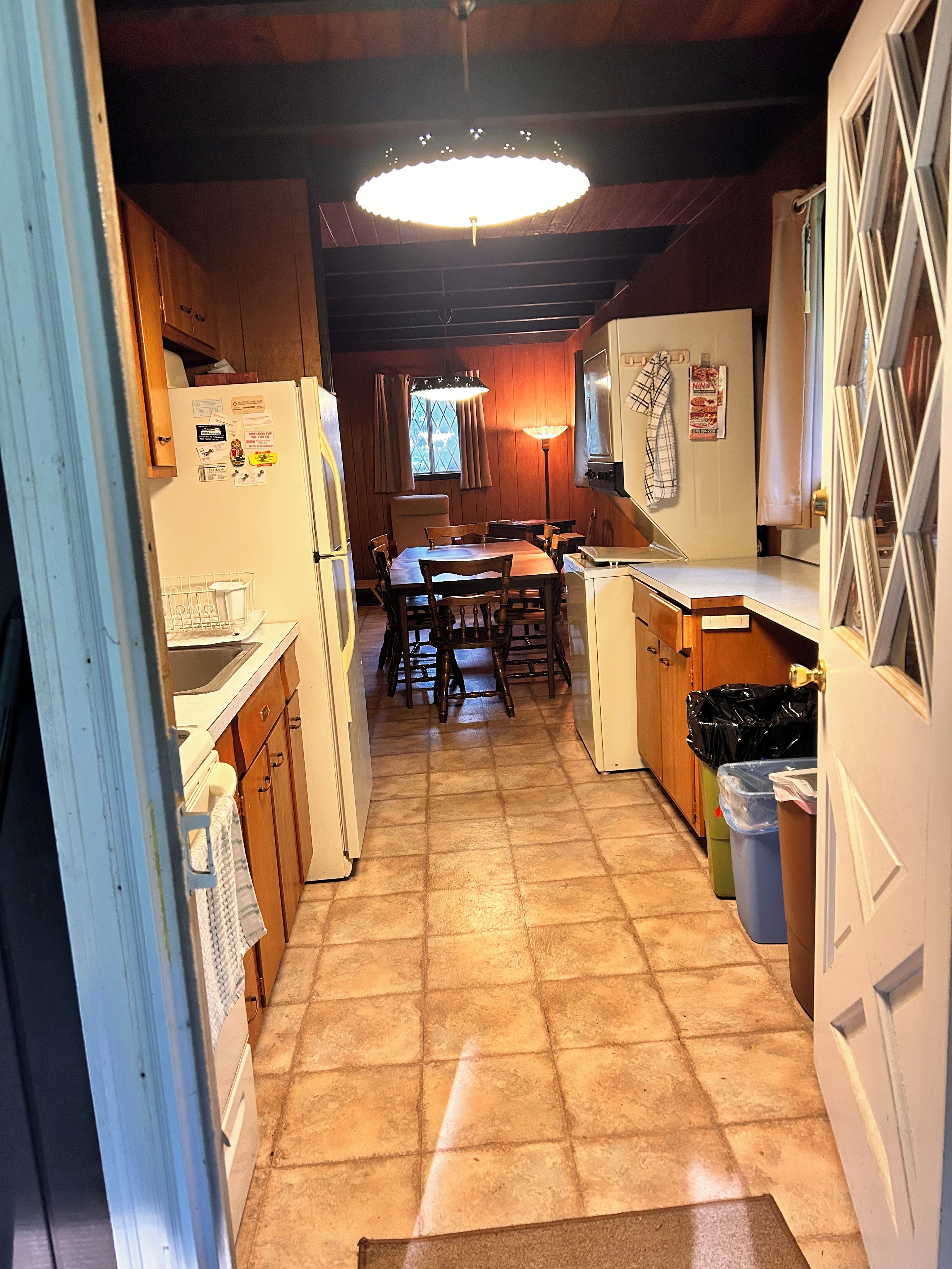 A kitchen with wooden cabinets, a dining table, and a hanging light fixture.
