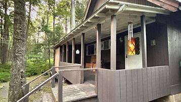 A cabin with a porch, wooden steps, and two potted plants.