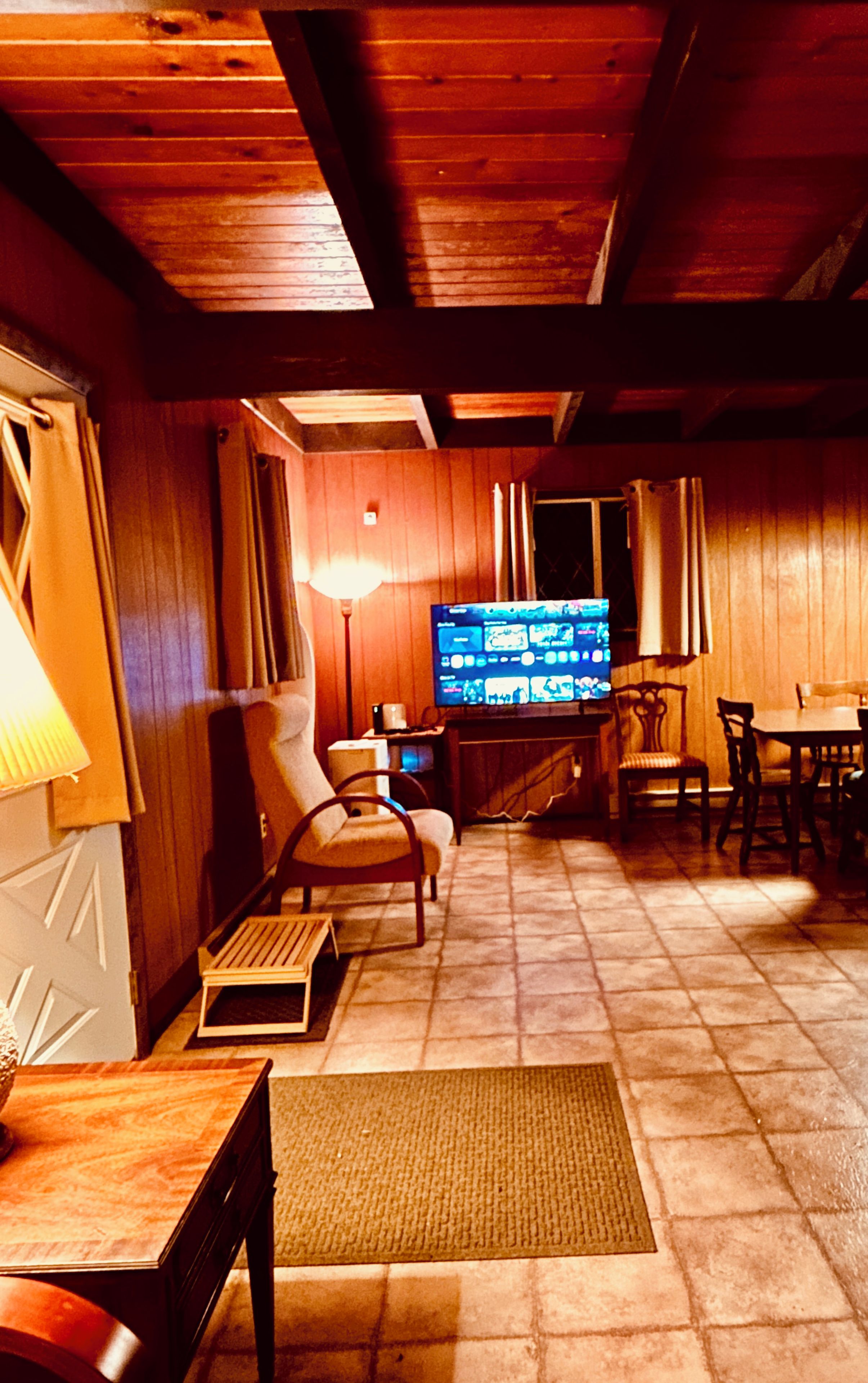 A cozy room with a television, wooden furniture, and a tiled floor.