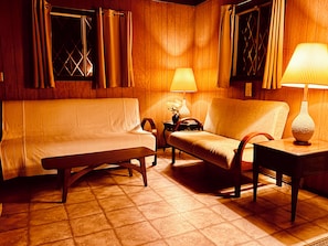 A cozy room with a sofa, a chair, a small table, and a lamp.