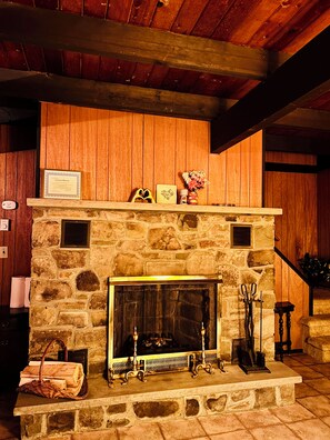 A stone fireplace with a mantel, a framed certificate, and a vase with flowers.