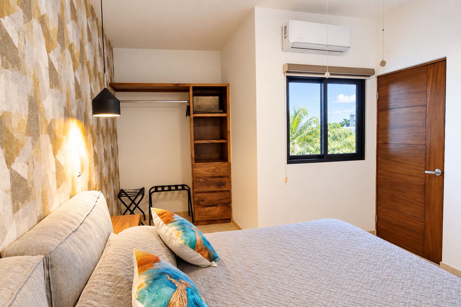 Quarto com cama, guarda-roupa, janela com vista e ar-condicionado fixado na parede.