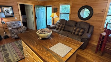 A wooden interior with a central island, a sofa, a lamp, and a ceiling fan.