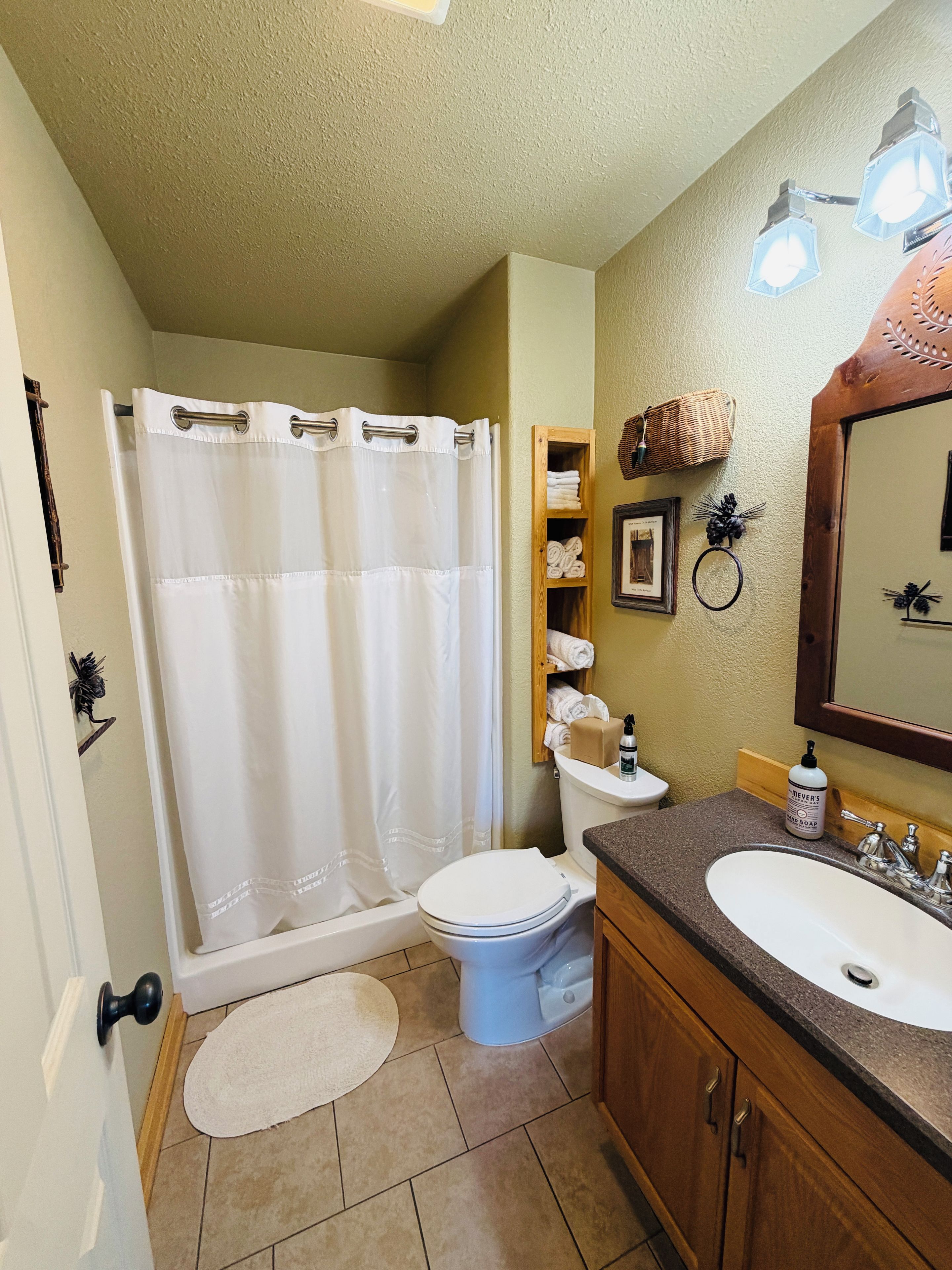A bathroom with a shower curtain, toilet, sink, and a mirror.