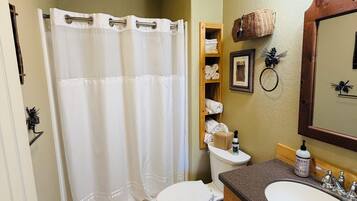 A bathroom with a shower curtain, toilet, sink, and a mirror.