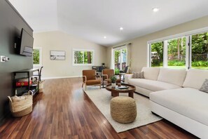 A modern living room with a sofa, chairs, a coffee table, and a TV mounted on the wall. - Hillside Haven | Beach Access, Game Room & Fire Pit (Lake Geneva)