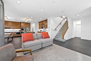 A modern interior with a grey sofa, wooden staircase, and a kitchen area. - 4b3b modern house in Ontario/Model Home/Two Living room/AC/WIFI/back yard (Ontario)
