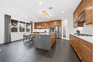 A modern kitchen with wooden cabinets, a central island, and a dining area with chairs. - 4b3b modern house in Ontario/Model Home/Two Living room/AC/WIFI/back yard (Ontario)