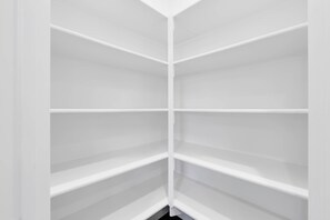 A corner of a room with white walls and a white floor, featuring a white built-in shelving unit with multiple compartments. - 4b3b modern house in Ontario/Model Home/Two Living room/AC/WIFI/back yard (Ontario)