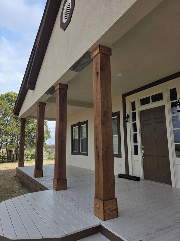 A covered outdoor area with wooden columns, a door, and windows.
