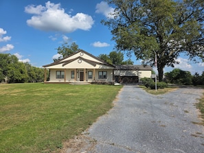 A single-story house with a front porch, a garage, and a driveway leading to the entrance. - Gated 3,600 Sq. Ft. Luxury Home on 15 acres by Hyundai with 2 car garage (Montgomery)