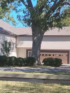A residential house with a large tree in front, a garage, and a well-maintained lawn. - Gated 3,600 Sq. Ft. Luxury Home on 15 acres by Hyundai with 2 car garage (Montgomery)