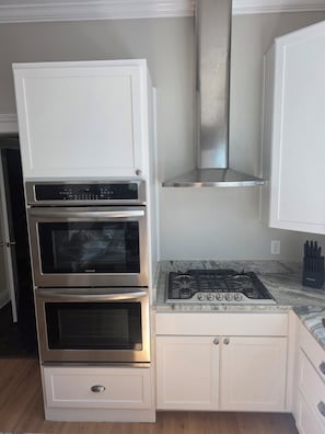 A kitchen with a built-in oven, a stovetop, and a stainless steel range hood.